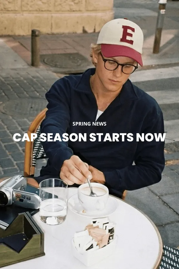 Ein Mann sitzt auf einer Holzkiste in einem Studio und trägt einen klassischen braunen Cowboyhut aus Filz mit breiter Krempe, ein dunkles Denimhemd und Jeans.